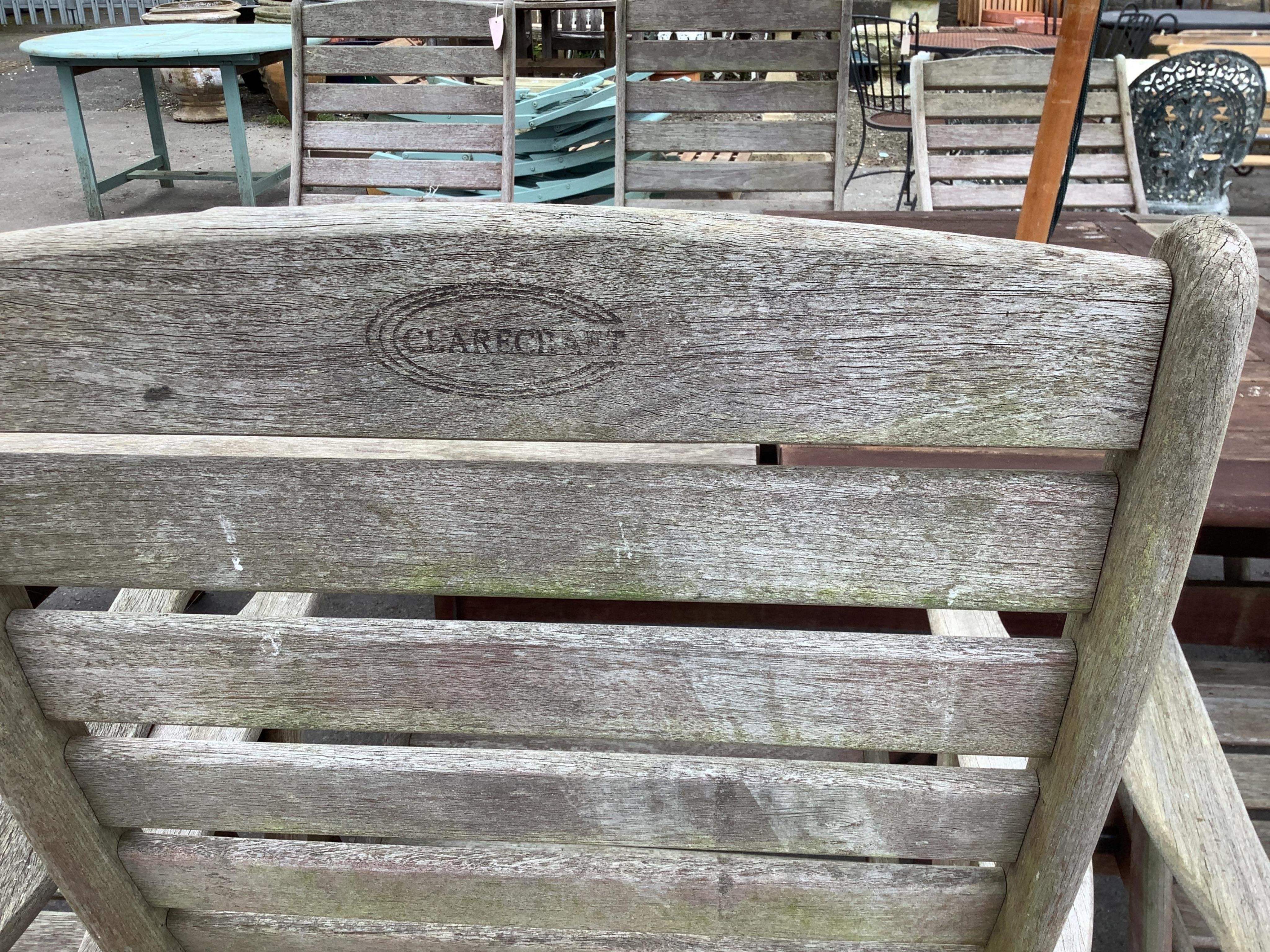 A large rectangular weathered teak extending garden table, width 256cm extended, depth 116cm, height 72cm together with a set of eight teak 'Clarecraft' elbow chairs, two with extending footrests, parasol, cast metal par